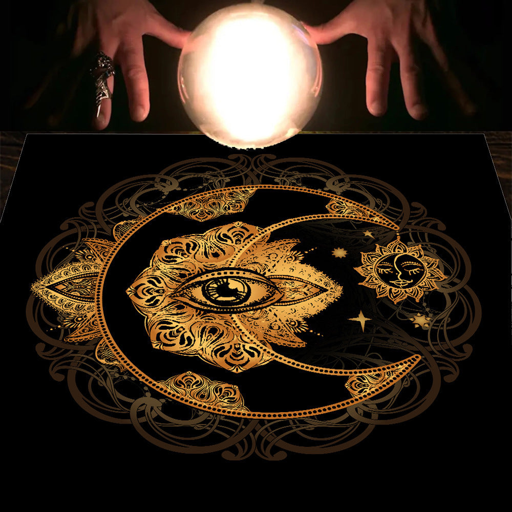 Decorative black surface with gold eye and moon design, illuminated by a glowing crystal ball.
