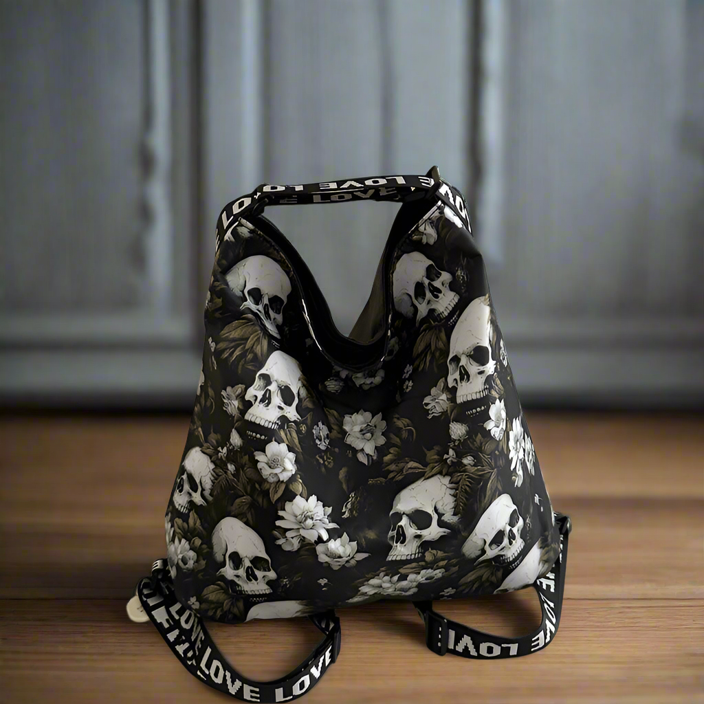 Black floral and skull patterned bag with 'LOVE' straps on a wooden surface.