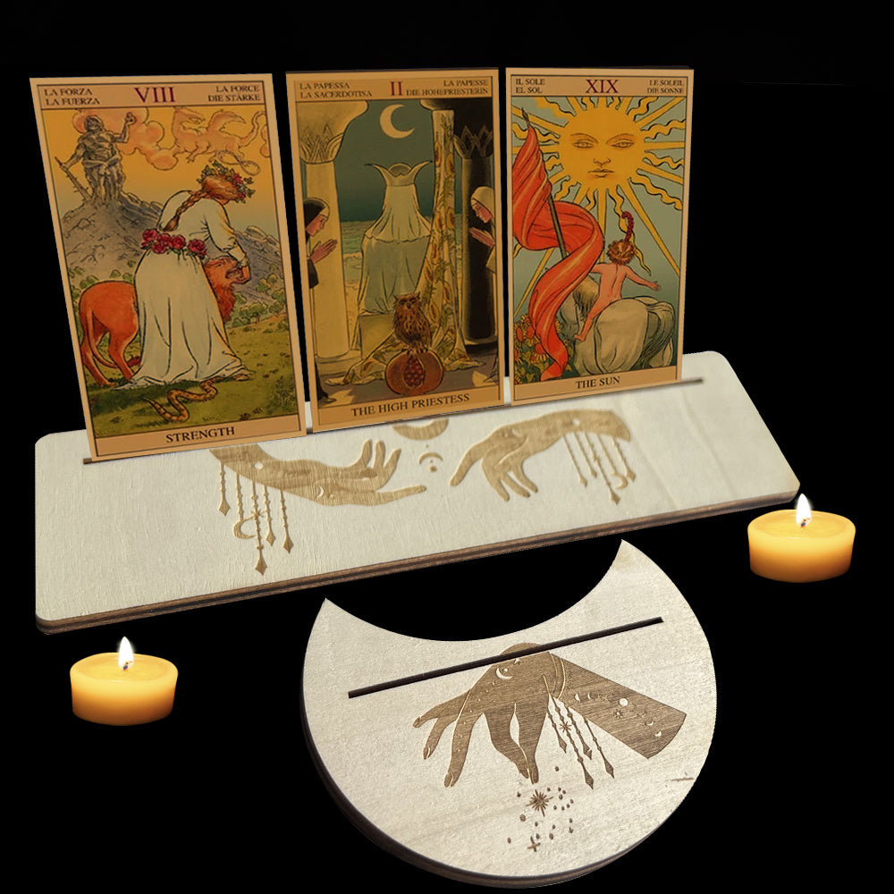 Three tarot cards on a stand with candles and a pentacle dish on a black background