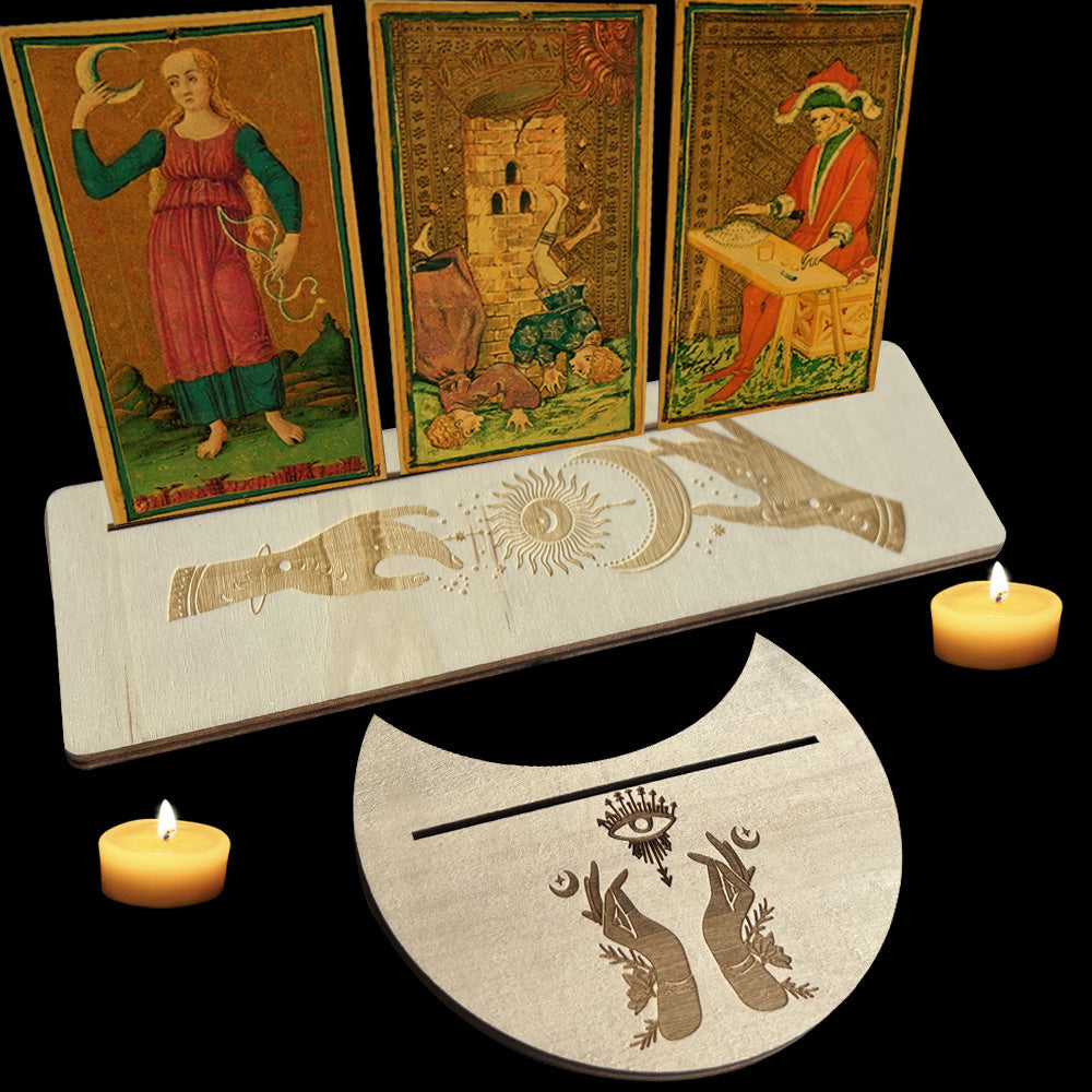 Three tarot cards on a stand with candles and a circular mat featuring astrological symbols.