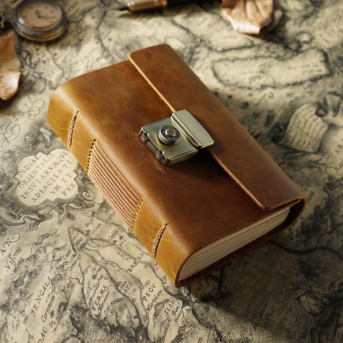 Brown leather notebook with a camera charm on an old map background