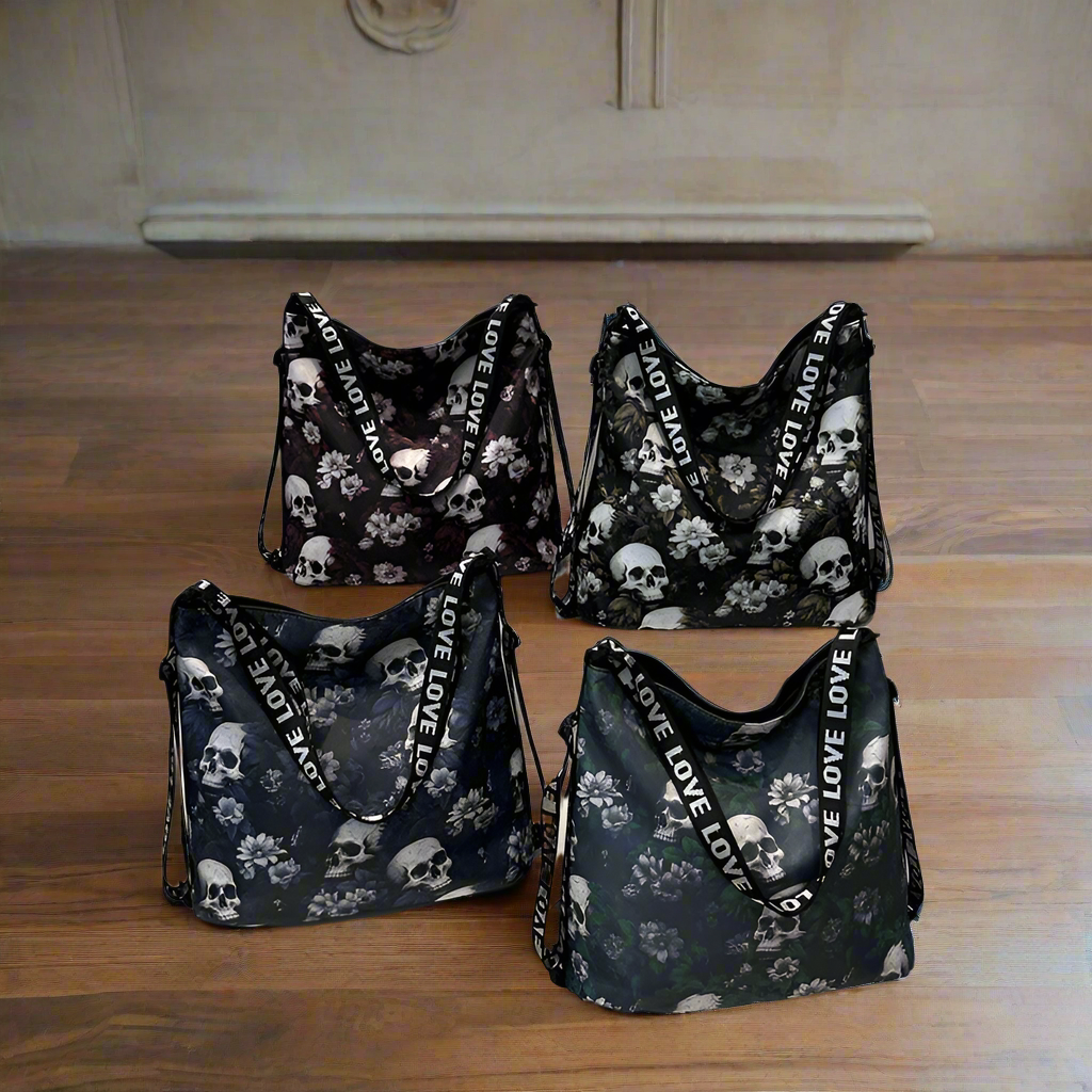 Four black handbags with skull and floral patterns on a wooden floor.