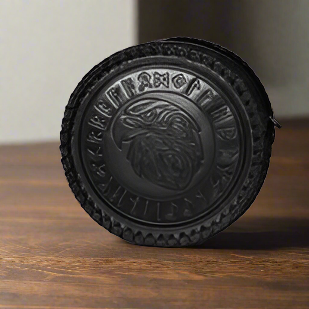 Black circular object with a detailed design on a wooden surface
