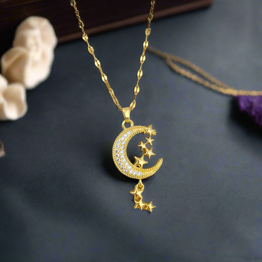 Gold necklace with a crescent moon and star pendant on a dark surface.