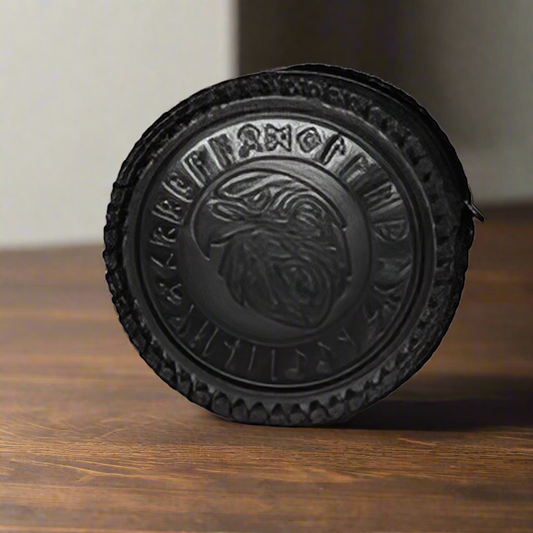 Black circular object with a detailed design on a wooden surface